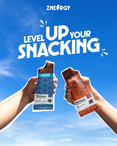 A bright, clear sky background featuring hands holding two protein bars in a celebratory, upward-reaching pose.